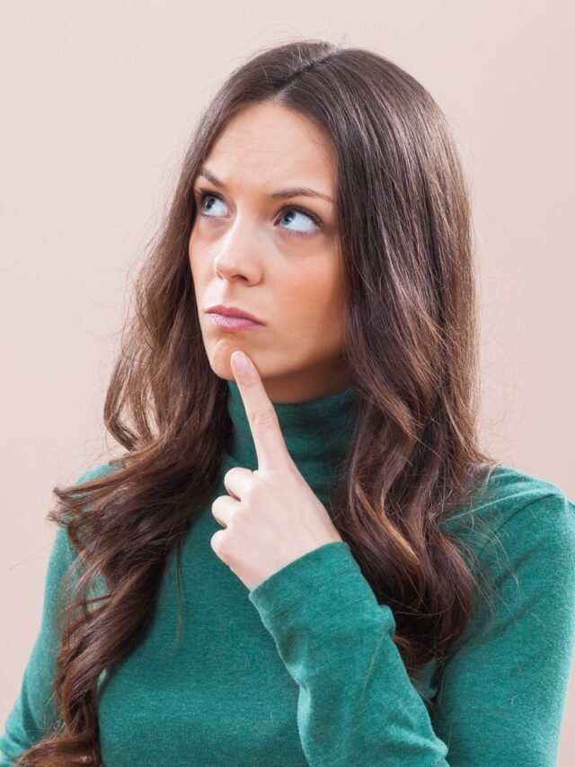 mulher-em-pé-com-o-dedo-no-rosto-pensando-em-como-parar-de-correr-atrás-de-alguém-que-não-me-quer